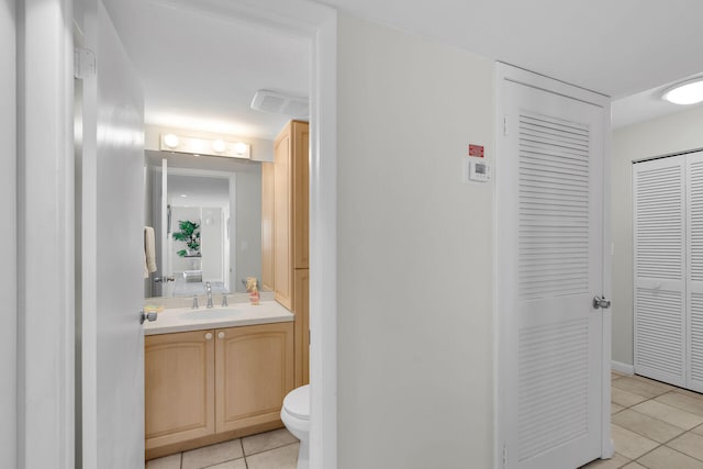 half bathroom with a closet, visible vents, toilet, vanity, and tile patterned flooring