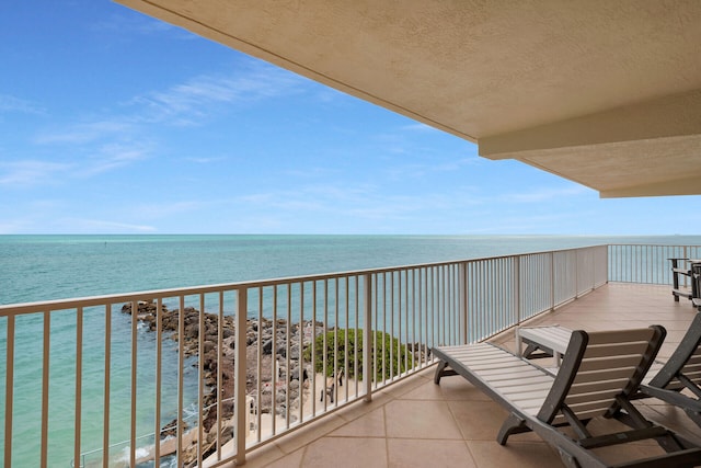 balcony with a water view and a view of the beach