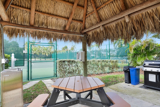 view of patio / terrace with a tennis court, a grill, a gate, fence, and a gazebo