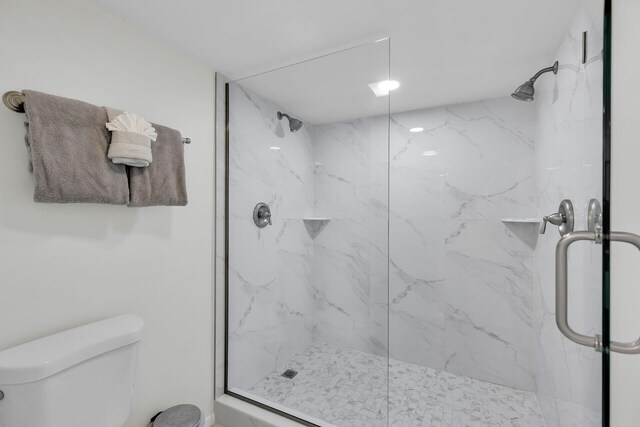 bathroom featuring toilet and a marble finish shower