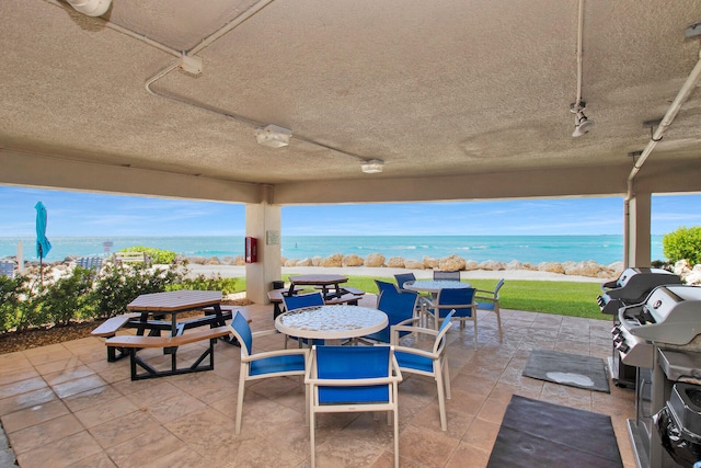 view of patio featuring a water view, outdoor dining area, and area for grilling