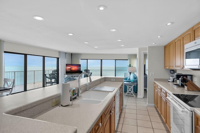 kitchen with white range with electric stovetop, open floor plan, light countertops, and a sink