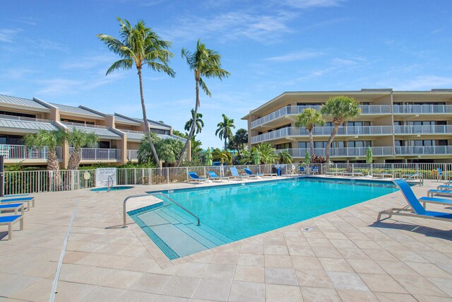 community pool with a patio area and fence