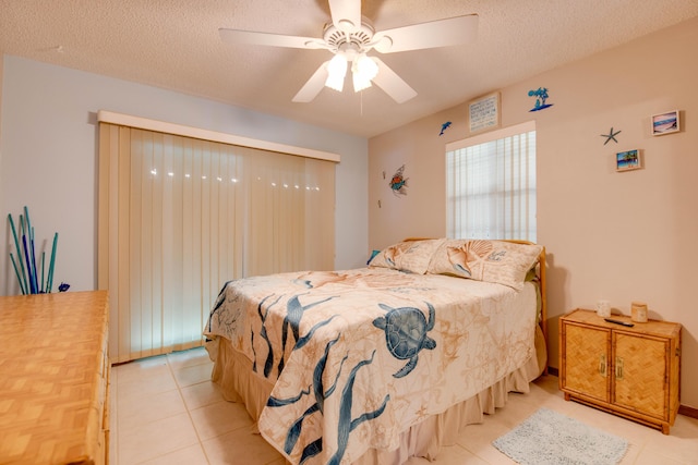 bedroom featuring light tile patterned floors, ceiling fan, and a textured ceiling