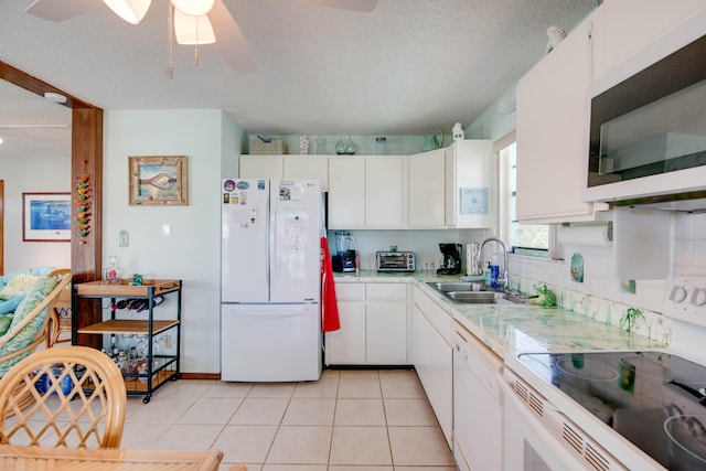 kitchen featuring light tile patterned floors, light countertops, white cabinetry, a sink, and white appliances