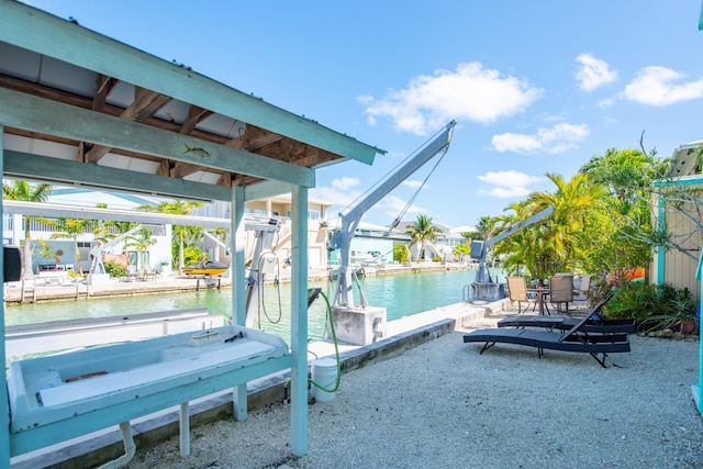 view of patio featuring a boat dock, a water view, and boat lift