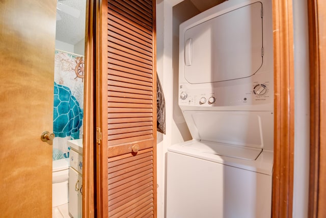 laundry area with laundry area, a textured ceiling, and stacked washer / drying machine