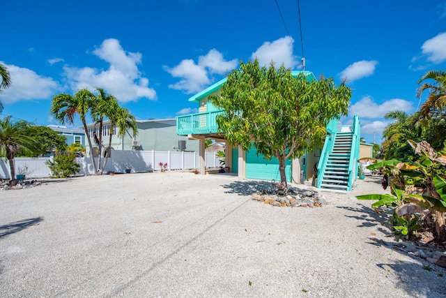 view of front of property featuring driveway, stairs, and fence