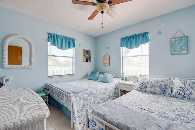 bedroom with multiple windows, a textured ceiling, and light tile patterned flooring