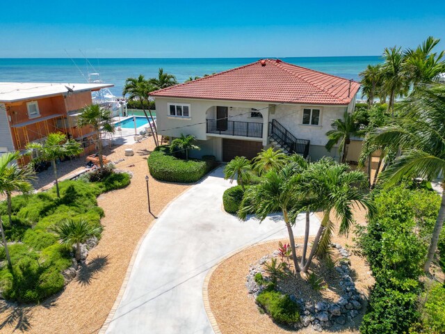 exterior space with a tile roof, stairs, a water view, and stucco siding