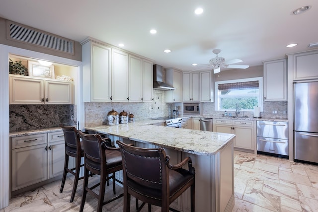 kitchen featuring ceiling fan, visible vents, backsplash, wall chimney range hood, and appliances with stainless steel finishes
