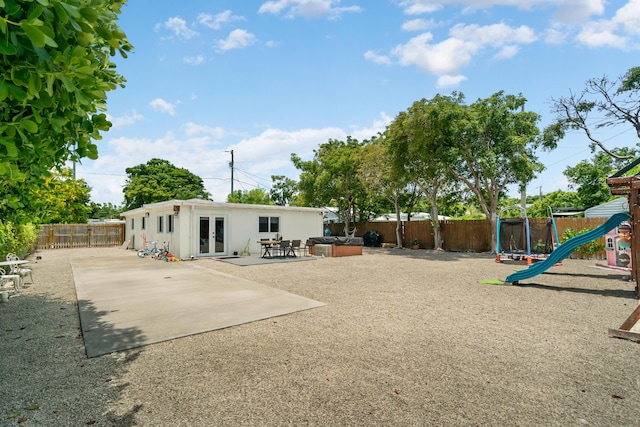 125 Harbor Dr, Key Largo, FL 33037 - rear view of house featuring french doors, a patio area, a fenced backyard, a playground, and stucco siding