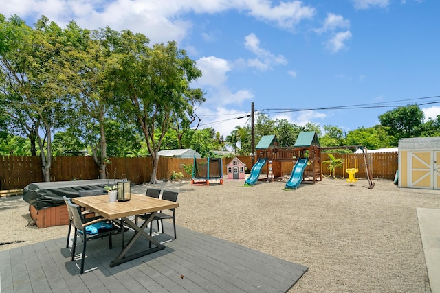125 Harbor Dr, Key Largo, FL 33037 - wooden deck featuring a hot tub, a storage unit, a fenced backyard, and a playground