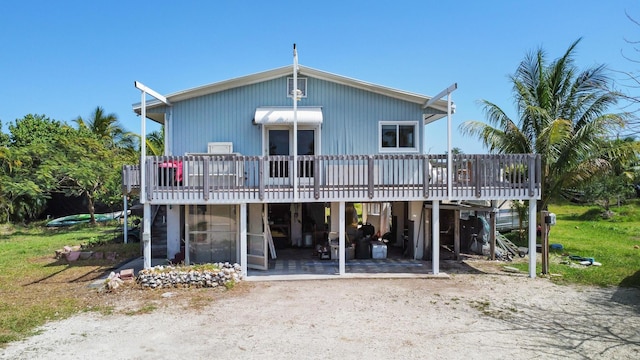 back of property featuring driveway, a patio area, a deck, and a carport