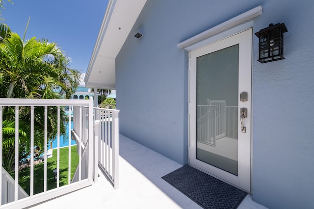 doorway to property featuring stucco siding and a balcony