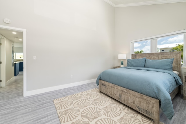 bedroom featuring crown molding, light wood-style flooring, and multiple windows