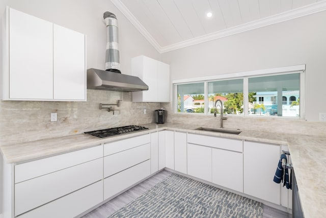 kitchen with crown molding, stainless steel gas cooktop, light countertops, wall chimney exhaust hood, and a sink