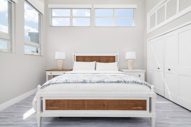 bedroom featuring a closet, light wood-style floors, and multiple windows