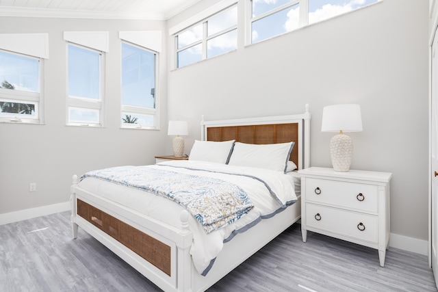 bedroom with light wood-style floors, baseboards, and ornamental molding