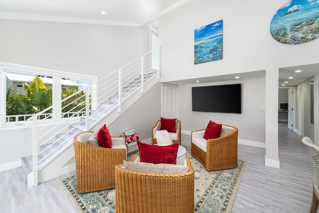 living area featuring crown molding, a high ceiling, stairs, and wood finished floors