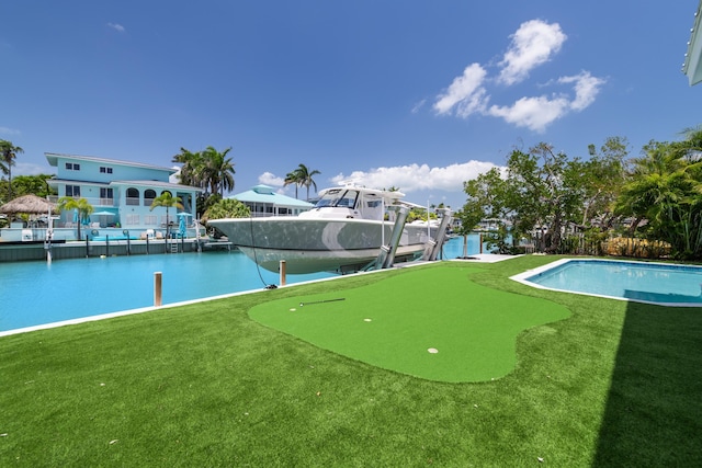 view of pool featuring a boat dock, a water view, and a yard