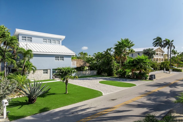 view of community with a lawn, fence, and driveway