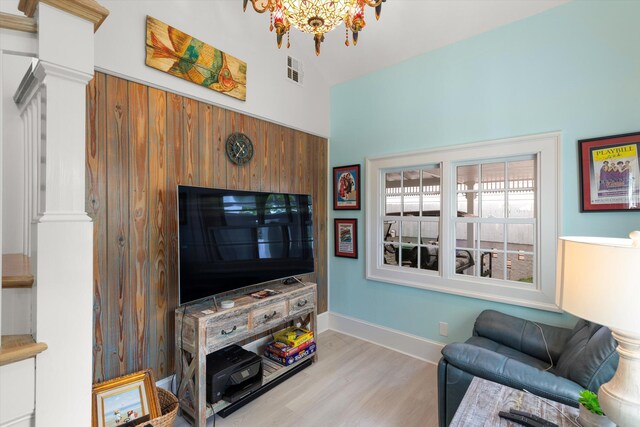 living room featuring a chandelier, light hardwood / wood-style floors, and ornate columns