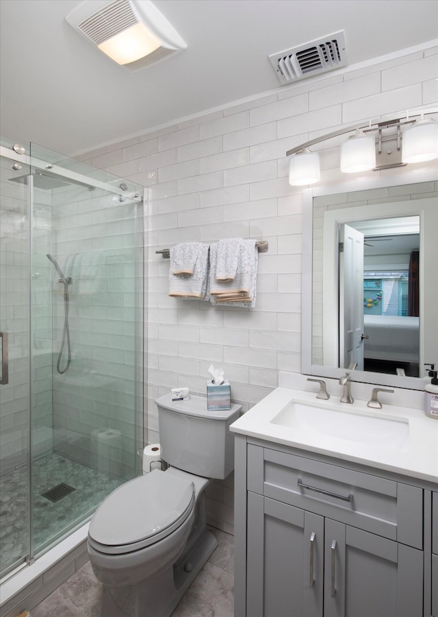 bathroom with vanity, a shower with shower door, tile walls, and toilet