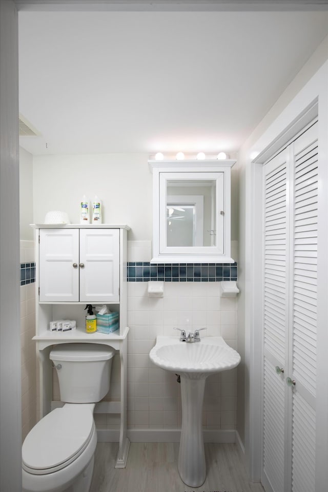 bathroom with tile walls, wood-type flooring, and toilet