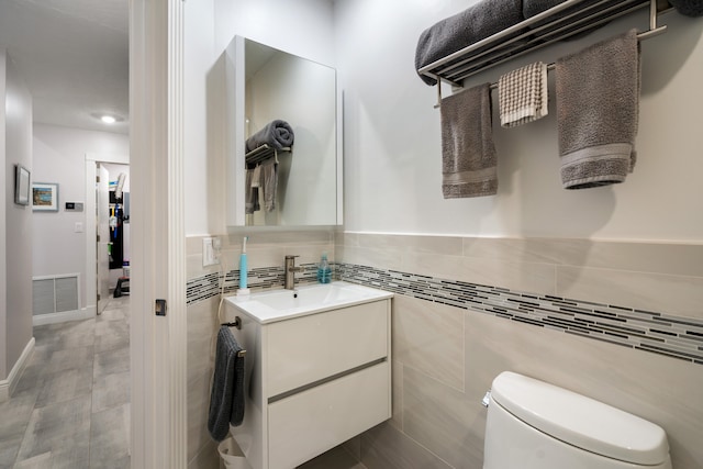 bathroom with vanity, tile walls, and toilet