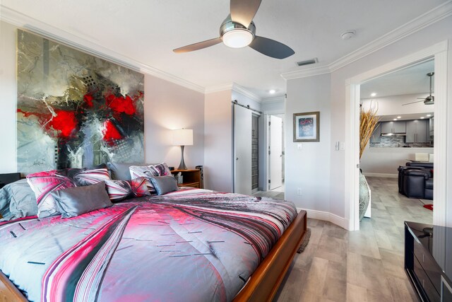 bedroom featuring crown molding, a barn door, ceiling fan, and light wood-type flooring