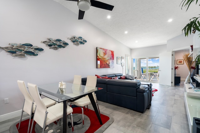 dining space with ceiling fan, vaulted ceiling, and a textured ceiling