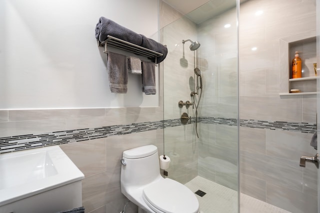 bathroom with a tile shower, tile walls, and toilet