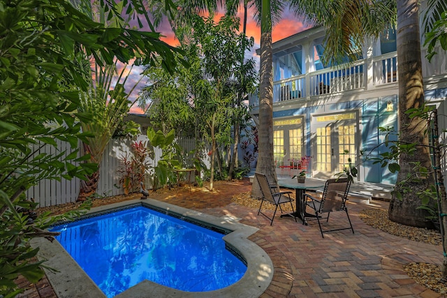 820 Carsten Ln, Key West, FL 33040 - pool at dusk featuring a patio area, a fenced backyard, and french doors