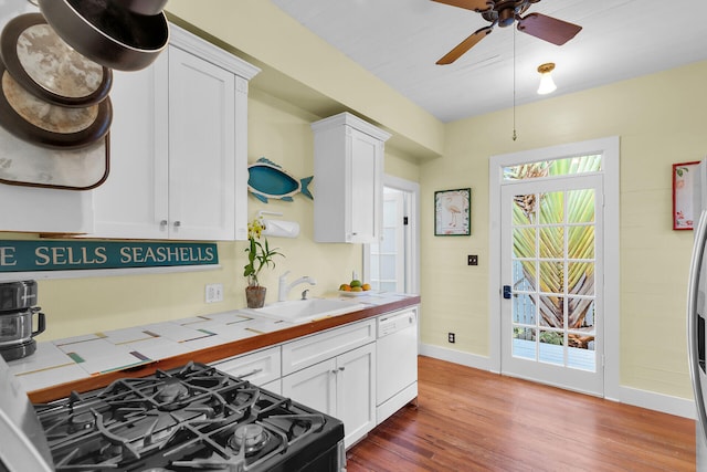 820 Carsten Ln, Key West, FL 33040 - kitchen with white dishwasher, gas range, tile countertops, wood finished floors, and white cabinetry
