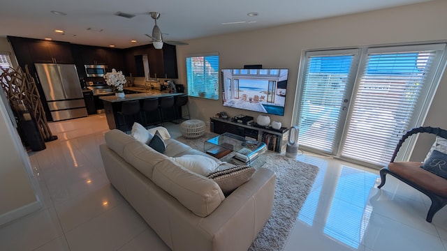 living area with light tile patterned floors, plenty of natural light, visible vents, and a ceiling fan