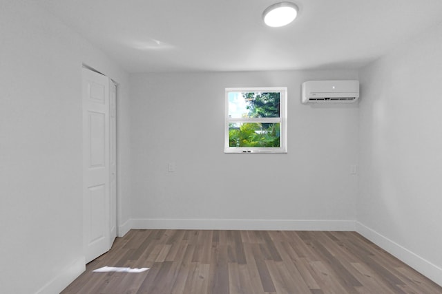 spare room featuring hardwood / wood-style flooring and a wall unit AC