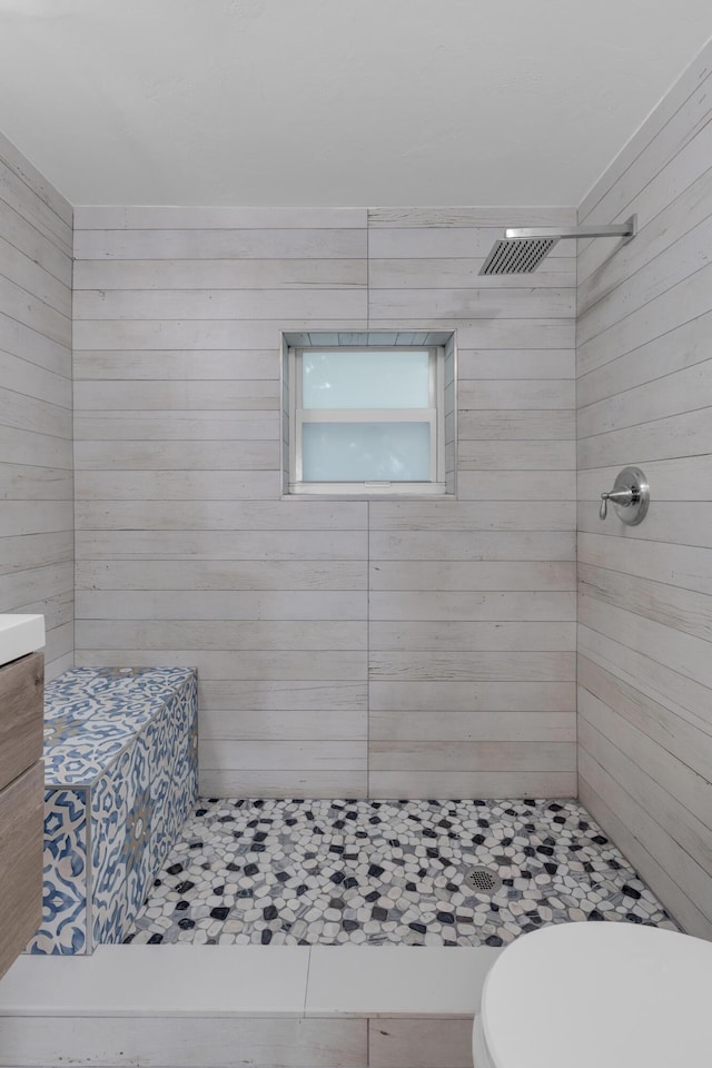 bathroom featuring vanity, a tile shower, and toilet