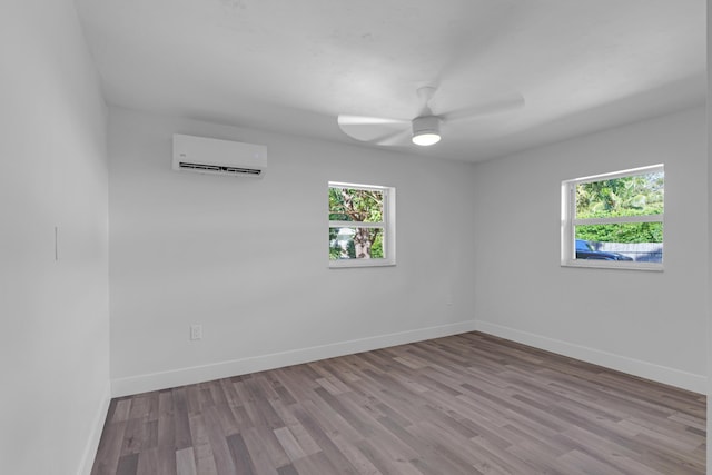 empty room featuring ceiling fan, a wall unit AC, and light wood-type flooring