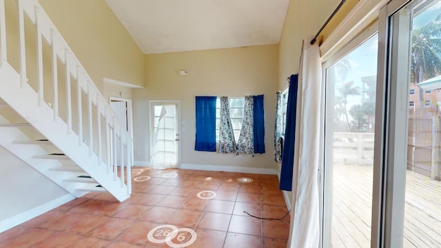 foyer featuring high vaulted ceiling and tile patterned flooring