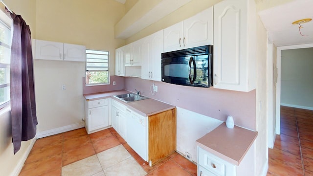 kitchen with white dishwasher, sink, light tile patterned floors, and white cabinets