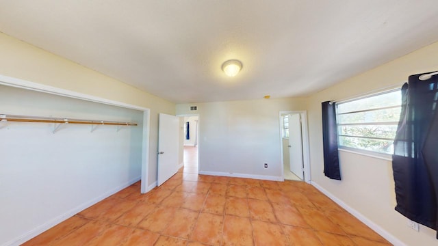 unfurnished bedroom with light tile patterned floors and a closet