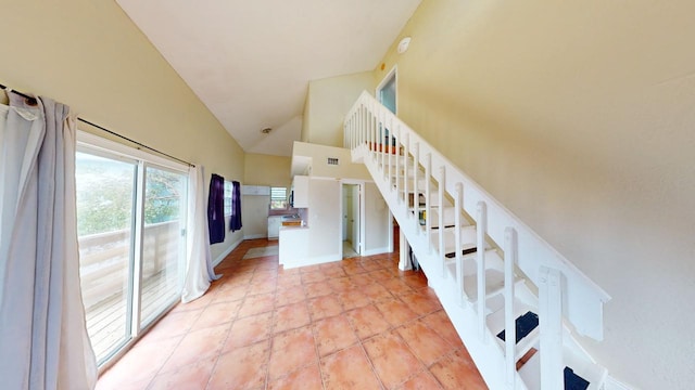 stairs with tile patterned flooring and high vaulted ceiling