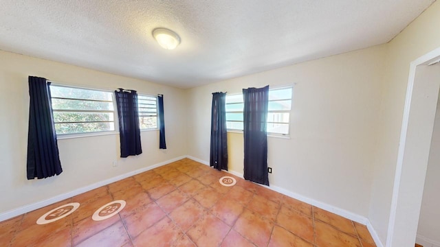 tiled empty room with plenty of natural light and a textured ceiling