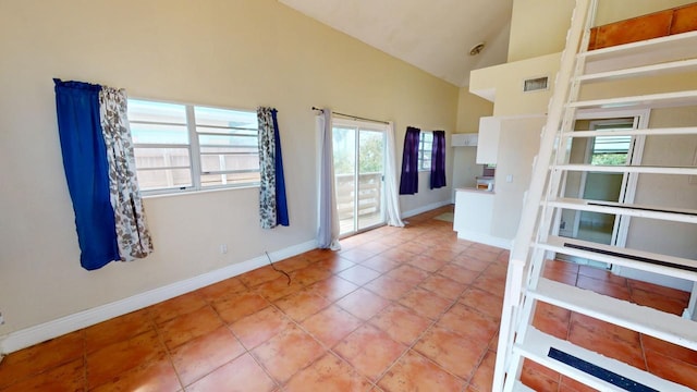 unfurnished room featuring light tile patterned floors and high vaulted ceiling