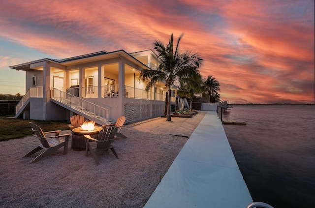 exterior space with a patio area, a water view, and an outdoor fire pit