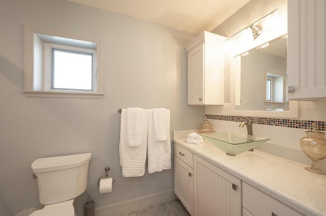 bathroom featuring vanity, decorative backsplash, and toilet