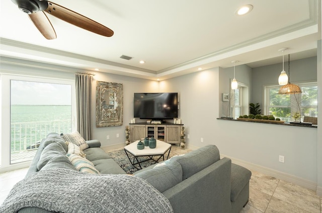 living room featuring crown molding, light tile patterned floors, a tray ceiling, and ceiling fan