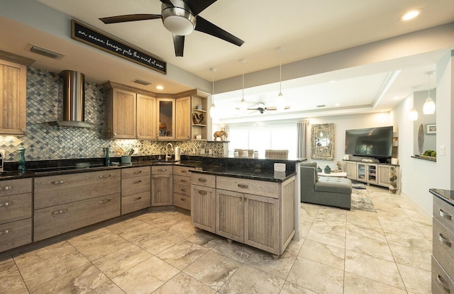 kitchen with pendant lighting, kitchen peninsula, dark stone countertops, and wall chimney exhaust hood