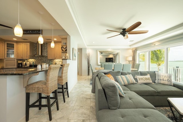 living room featuring crown molding, ceiling fan, and a raised ceiling